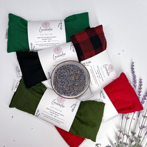 May include: Assortment of six lavender eye pillows in various colours, including green, black, red, and plaid. The pillows are filled with flax seed and organic lavender flowers. The text on the label reads "Lavender Eye Pillow".