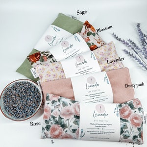 May include: Assortment of lavender eye pillows in various floral patterns, including sage, blossom, lavender, dusty pink, and rose. Each pillow is filled with flax seed and organic lavender flowers. The text on the pillows reads "Lavender Eye Pillow".