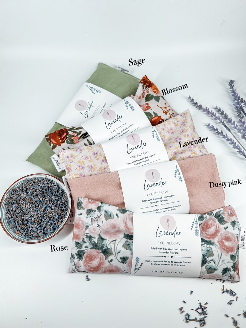 May include: Assortment of lavender eye pillows in various floral patterns, including sage, blossom, lavender, dusty pink, and rose. Each pillow is filled with flax seed and organic lavender flowers. The text on the pillows reads "Lavender Eye Pillow".