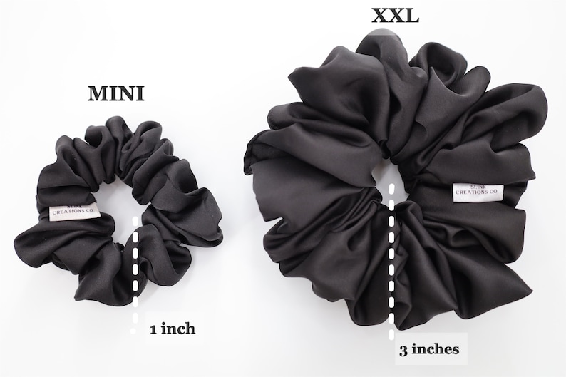 May include: Two black satin scrunchies, one measuring 1 inch in diameter and the other measuring 3 inches in diameter. The larger scrunchie has the text "Silk Creations Co." printed on it.