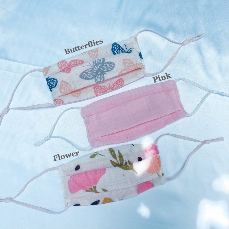 May include: Three face masks with adjustable ear loops. One mask is pink, another has a butterfly pattern, and the third has a floral design. The word "Butterflies", "Pink", and "Flower" are printed on the image.