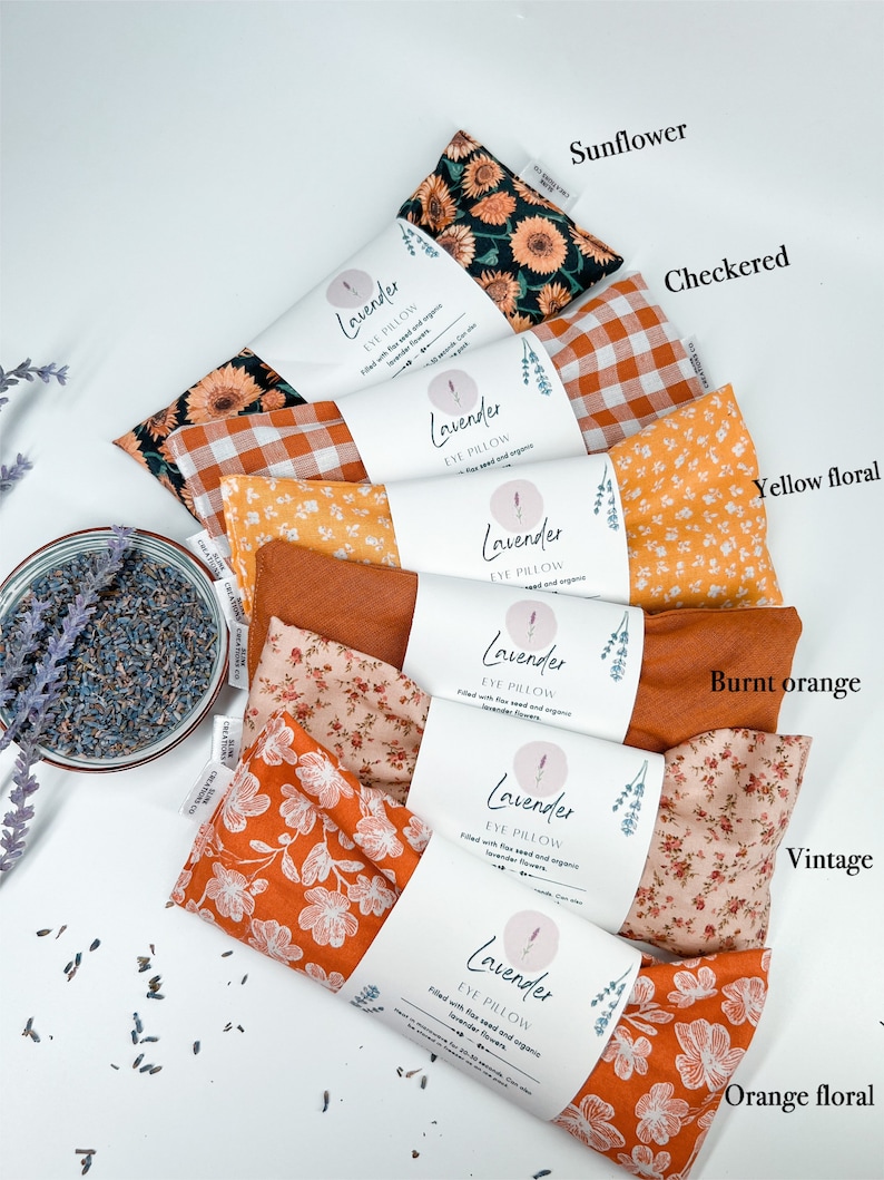 May include: Six eye pillows with different fabric patterns, including sunflower, checked, yellow floral, burnt orange, vintage, and orange floral. Each pillow is labelled "Lavender Eye Pillow" and filled with flax seed and organic lavender flowers.