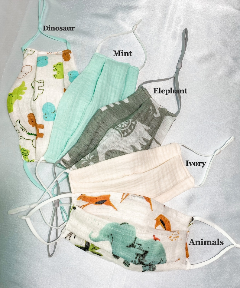 May include: Assortment of face masks in various colors and patterns. Designs include dinosaurs, elephants, and other animals. The masks have adjustable ear loops and are made of a soft, breathable fabric. The masks are labeled "Dinosaur", "Mint", "Elephant", "Ivory", and "Animals".
