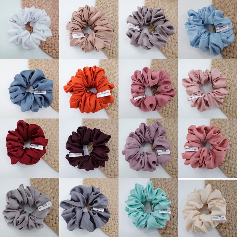 May include: Assortment of 12 colorful scrunchies made of soft fabric. The scrunchies are arranged in a grid pattern on a woven background.