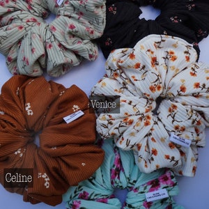 May include: Five different patterned hair scrunchies in various colors, including green, black, white, brown, and blue. Each scrunchie has a small white tag with the text "SLINK CREATIONS CO."