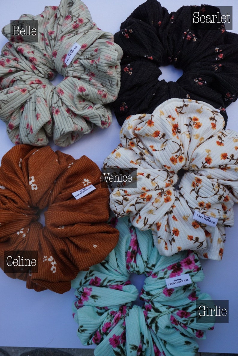 May include: Five different patterned hair scrunchies in various colors, including green, black, white, brown, and blue. Each scrunchie has a small white tag with the text "SLINK CREATIONS CO."