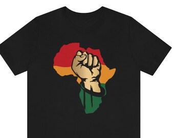 Può includere: Maglietta nera con una grafica di un pugno alzato su un contorno del continente africano in rosso, giallo e verde.