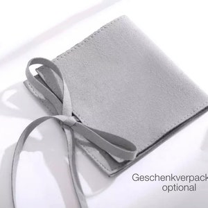 Puede incluir: Una bolsa de gamuza gris con un lazo. La bolsa es para envolver regalos y es opcional.