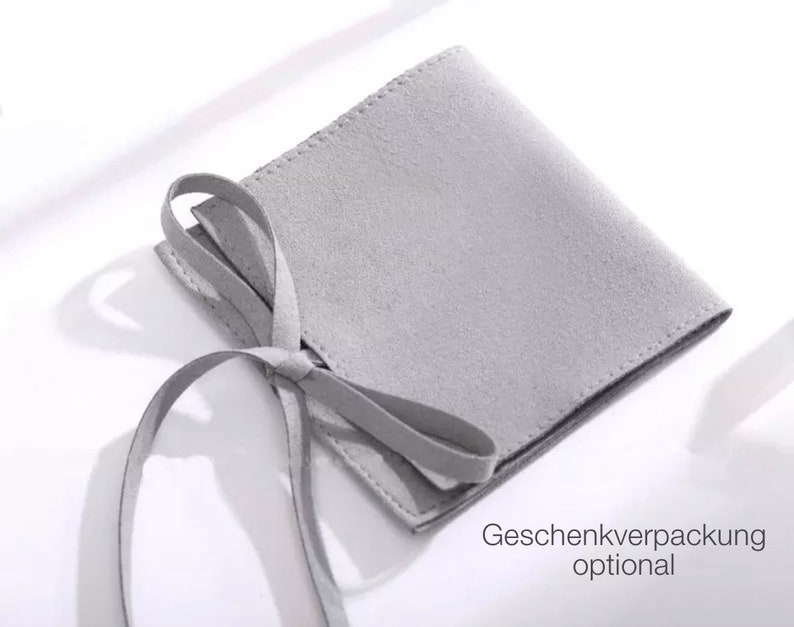 Puede incluir: Una bolsa de gamuza gris con un lazo. La bolsa es para envolver regalos y es opcional.