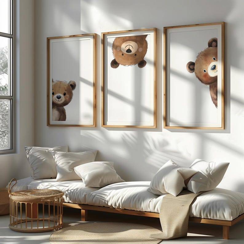 May include: Three framed illustrations of brown bears peeking out from behind the edges of the frames. The frames are wooden and have a light brown finish. The illustrations are in a minimalist style with a white background.