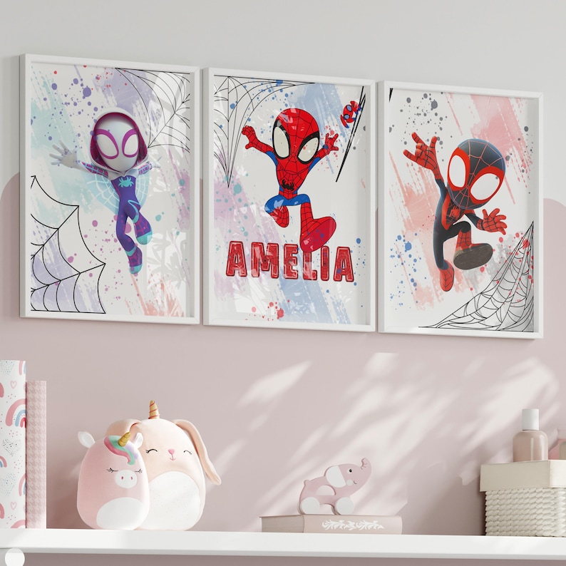 May include: Three framed prints featuring cartoon superheroes with a watercolor background. The prints feature Spider-Man, Spider-Gwen, and Miles Morales. The middle print has the name "Amelia" written below the image.