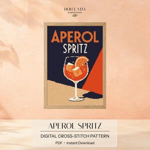 Könnte beinhalten: Ein gerahmtes Kreuzstichmuster mit dem Text APEROL SPRITZ in orangefarbenen und weißen Buchstaben. Das Design zeigt ein Stielglas gefüllt mit einem orangefarbenen Cocktail, Eiswürfeln und einer Orangenscheibe vor dunkelblauem und rotem Hintergrund.