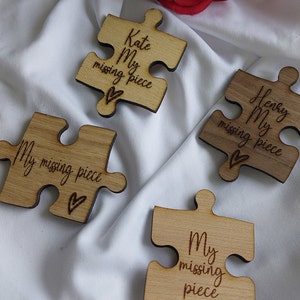 May include: Four wooden puzzle pieces with the text "My missing piece" and a heart symbol. The pieces are in different shades of brown and have a natural wood finish.