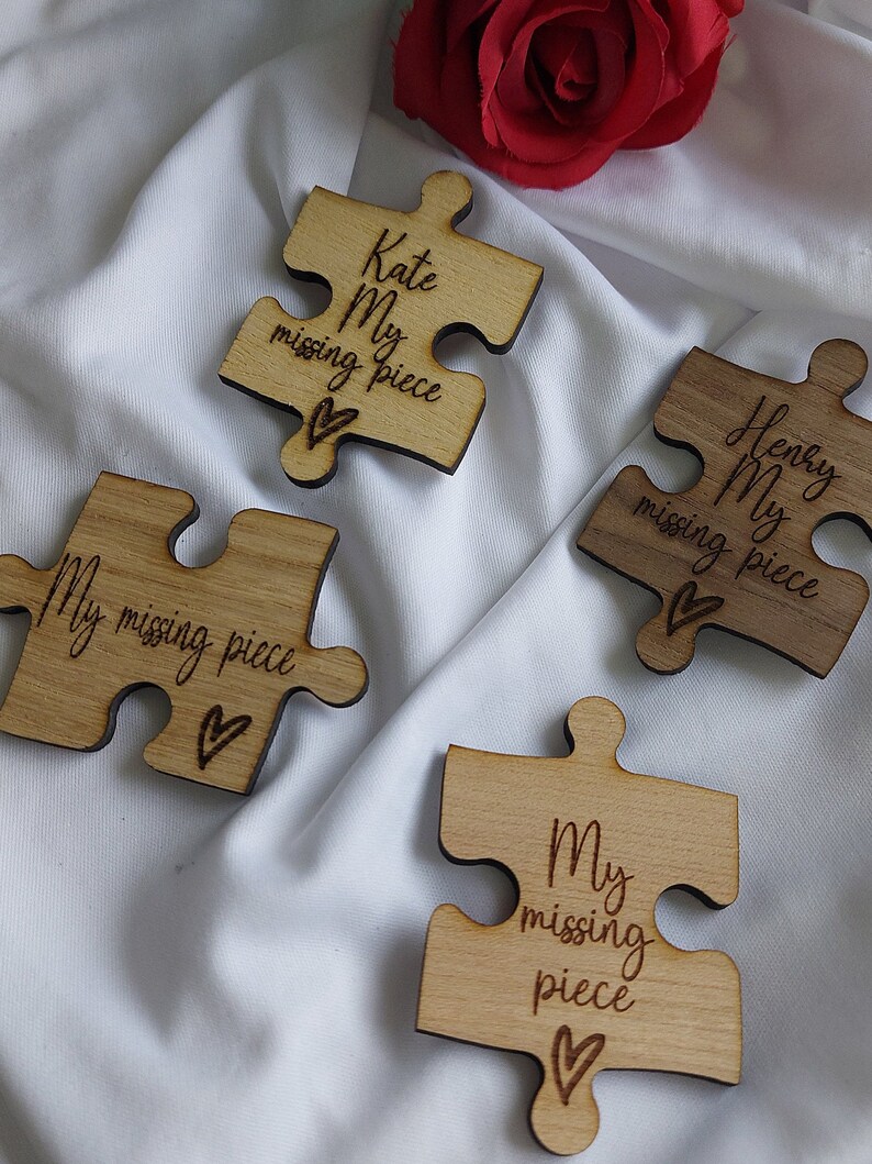 May include: Four wooden puzzle pieces with the text "My missing piece" and a heart symbol. The pieces are in different shades of brown and have a natural wood finish.