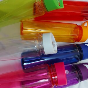 Puede incluir: Seis botellas de agua reutilizables en varios colores, incluyendo transparente, verde, naranja, azul y morado. Las botellas tienen tapas de diferentes colores y algunas tienen asas de transporte.