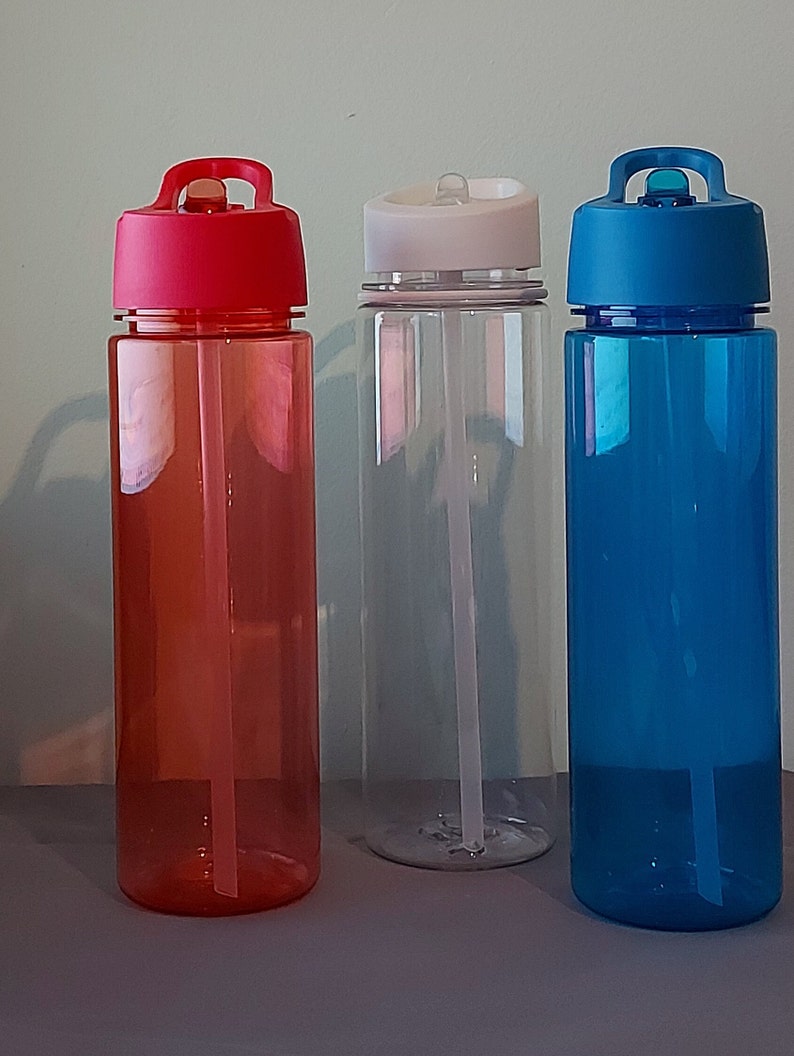 Puede incluir: Tres botellas de agua reutilizables con pajitas incorporadas. Las botellas son de pl&aacute;stico transparente y tienen tapas de diferentes colores: rojo, blanco y azul.