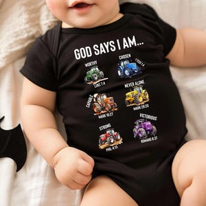 Könnte beinhalten: Schwarzer Baby-Body mit dem Text "GOD SAYS I AM..." und Traktorillustrationen. Der Body zeigt die Wörter "Worthy", "Chosen", "Capable", "Strong", "Never Alone" und "Victorious" mit entsprechenden Bibelversen.