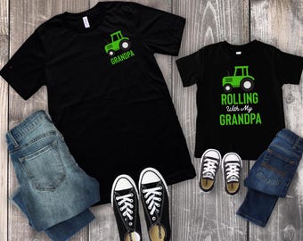 May include: Black t-shirts with green tractor graphics and text that reads "GRANDPA" and "Rolling With My Grandpa." The image also includes blue jeans and black Converse sneakers.