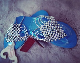 Chanclas Havaianas originales, de color azul claro, decoradas a mano con pedrería y cuentas, y acabadas con delicado hilo encerado.