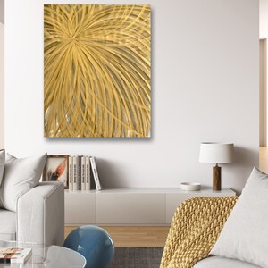 Puede incluir: Pintura abstracta con un esquema de color dorado y amarillo. La pintura presenta un patrón radial de líneas que irradian hacia afuera desde el centro.