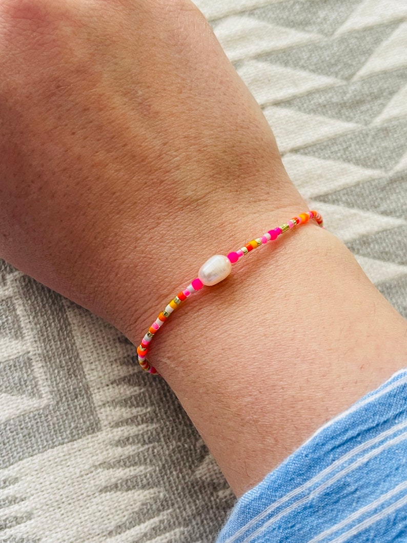 Armband Fein Makramee mit Neonperle Pink Orange Buntes Armband Minimalistisch mit Süßwasserperle oder Smiley. Bild 1