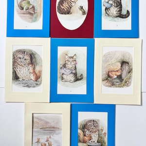 May include: A collection of framed vintage illustrations featuring animals. The images include a mouse, kittens, an owl, and squirrels. The frames are in various colors, including blue, red, and cream, with white matting. The illustrations have a classic, storybook style.