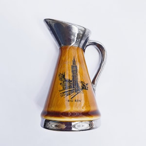 May include: A brown ceramic jug with a silver top and handle. The jug features a black and white illustration of Big Ben and the Houses of Parliament. The text "BIG BEN" is printed on the front of the jug.