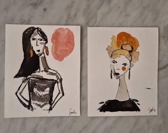 May include: Two watercolor paintings of women with black and white outlines. The woman on the left has long black hair and is wearing a black top. The woman on the right has a yellow and orange hairpiece and is wearing a black top. Both women have orange earrings.