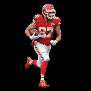 Op de afbeelding: Een American footballspeler in een rood en wit uniform, nummer 87, rent met de bal. De speler draagt een rode helm, rode sokken en rode schoenplaatjes. Het uniform heeft gele accenten.