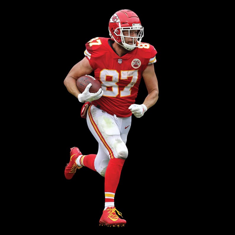Op de afbeelding: Een American footballspeler in een rood en wit uniform, nummer 87, rent met de bal. De speler draagt een rode helm, rode sokken en rode schoenplaatjes. Het uniform heeft gele accenten.