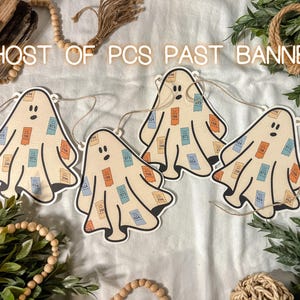 May include: A banner with four ghost-shaped cutouts, each adorned with colorful rectangles and small numbers. The banner reads "GHOST OF PCS PAST BANNER" in white letters. The ghosts are strung together with twine.