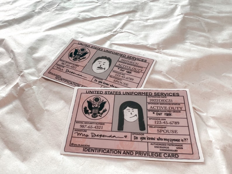 May include: Two pink and grey Identification and Privilege Cards from the United States Uniformed Services. Each card features a cartoon illustration of a person and includes text such as "Active Duty" and "Spouse."