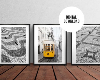 May include: Three black and white framed photographs of a cobblestone street in Lisbon, Portugal. The center photo shows a yellow tram traveling up a hill. The other two photos show the cobblestone street with pigeons.