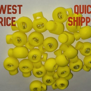 May include: A pile of 25 yellow plastic toggle clasps with a metal spring inside each clasp.