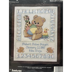 May include: Cross-stitch kit with a teddy bear, giraffe, and duck design. The kit includes the alphabet, numbers, and the name "Robert Allen Knight" with a birthdate and weight. Finished size is 27.9 cm x 35.6 cm. The kit includes instructions.