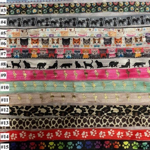 Op de afbeelding: Een set van 17 kleurrijke elastiekjes voor haar met verschillende patronen, waaronder katten, flamingo's, pootjes en luipaardprint.