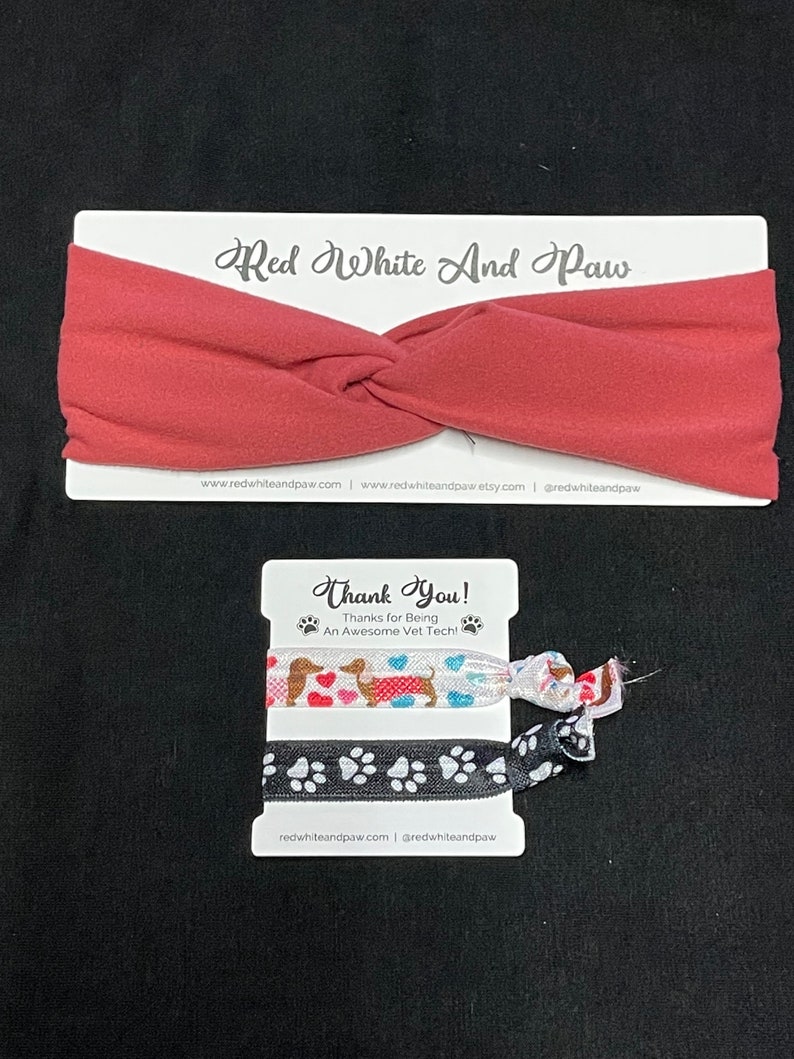 May include: Two colorful hair scrunchies with a dachshund and paw print designs. The scrunchies are packaged on a white card with the text "Thank You! Thanks for Being An Awesome Vet Tech!" and the website address "redwhiteandpaw.com".