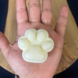 May include: A white paw-shaped soap bar with four toes and a pad.
