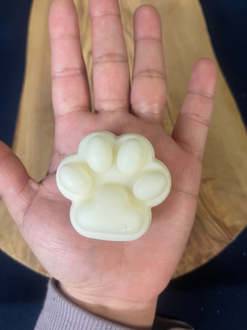 May include: A white paw-shaped soap bar with four toes and a pad.