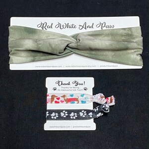 May include: A set of two hair scrunchies with a green and white tie-dye headband. The scrunchies feature a dachshund dog design with hearts and paw prints. The packaging includes the text "Red White And Paw" and "Thank You! Thanks for Being An Awesome Vet Tech!"