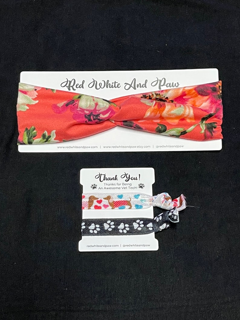 May include: A set of two hair scrunchies with a floral print and a paw print design. The scrunchies are packaged on a card with the text "Red White And Paw" and "Thank You! Thanks for Being An Awesome Vet Tech!"