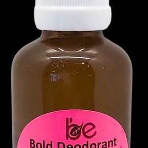 Könnte beinhalten: Eine braune Glasflasche mit einem weißen Sprühkopf und einem pinkfarbenen und schwarzen Etikett. Das Etikett lautet "Bold Deodorant 24 hrs Freshness" und listet die Inhaltsstoffe auf: Hamamelis, Aloe Vera, Pfeilwurzel, Kokosnuss, Natron, Teebaum, Lavendel, Rosmarin. Das Etikett enthält auch das Nettovolumen (50 ml) und den Preis (9,99 £). Die Flasche ist mit dem Firmennamen "BRUSH Europe" und den Kontaktdaten versehen.