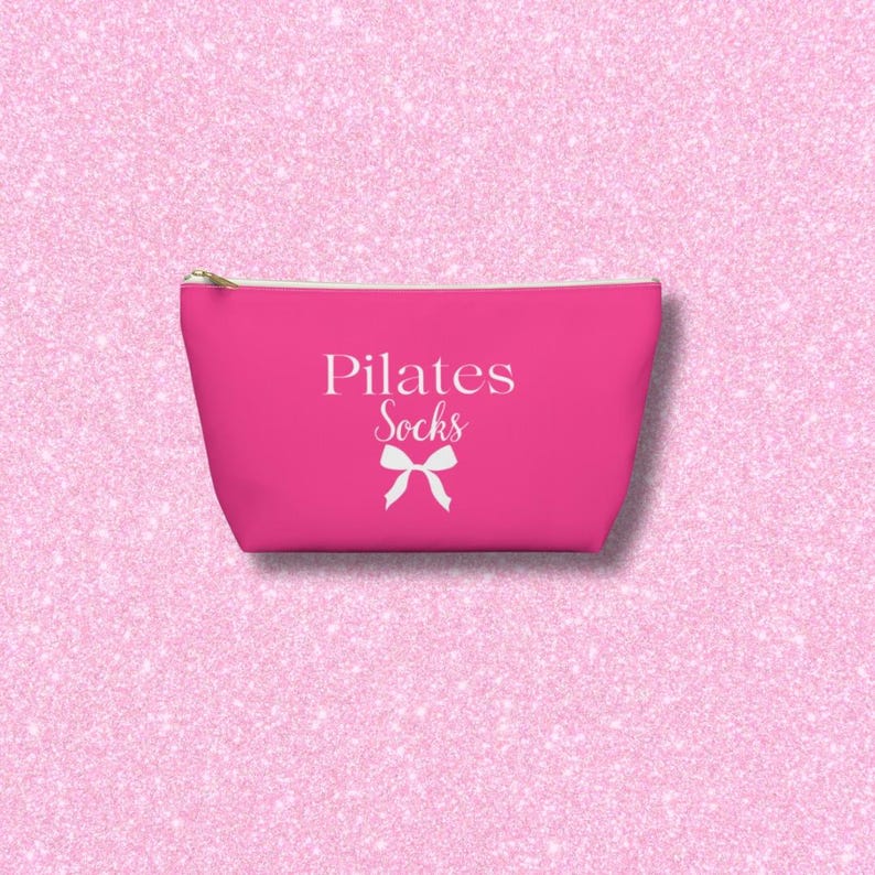 May include: A hot pink zippered pouch with a white bow and the text "Pilates Socks" printed on it.