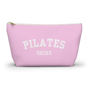 May include: A pink zippered pouch with the text "PILATES SOCKS" in white.
