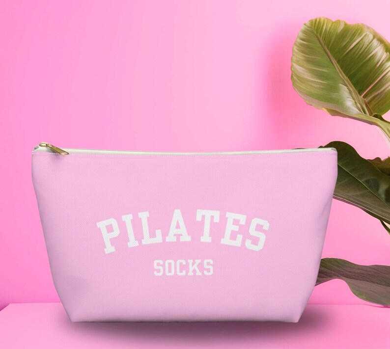 May include: A pink zippered pouch with the text "PILATES SOCKS" in white.