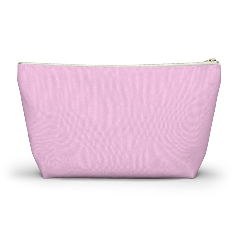May include: A light pink zippered pouch with a white zipper.