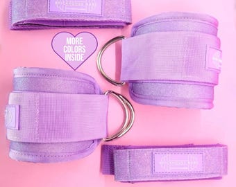 May include: Purple ankle weights with adjustable straps and a silver metal ring. The straps have the text "Brickhouse Babe" printed on them.
