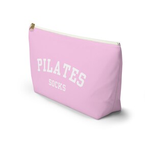 May include: Pink zippered pouch with the text "PILATES SOCKS" in white.