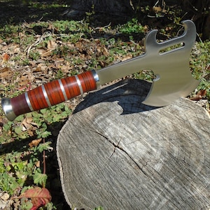 May include: A silver axe with a wooden handle. The axe has a bottle opener and a guitar-shaped cutout in the blade.