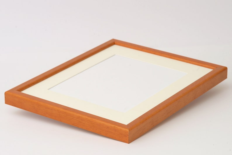 May include: A wooden picture frame with a light brown finish and a white mat. The frame is empty and ready for a photo.